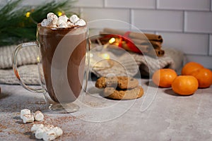 hot chocolate in a glass mug with mini marshmallows on grey table, blurred xmas background