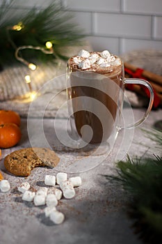 hot chocolate in a glass mug with mini marshmallows on grey table, blurred xmas background