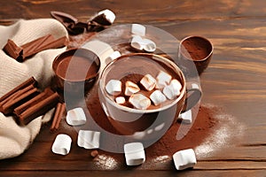 hot chocolate with marshmallows and cocoa powder in cup on wooden table