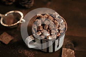 Hot chocolate with marsmallow candies, winter warming sweet drink in mug on wooden background, selective focus