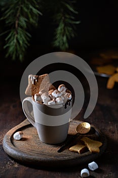 Hot chocolate mug decorated with marshmallows and star-shaped gingerbread on the table