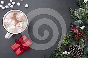 Hot chocolate mugs with marshmallows and christmas gift boxes. Flat lay with fir branches. Gray background. Copy space