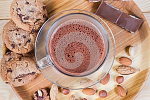 Hot chocolate, nuts and confections on wooden dish, top view