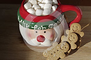 hot chocolate Santa Clause cute mug with marshmallows, and gingerbread cookies on wooden table