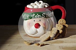 Hot chocolate Santa Clause cute mug with marshmallows, and gingerbread cookies on wooden table