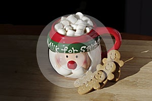 Hot chocolate Santa Clause cute mug with marshmallows, and gingerbread on wooden table with copy space