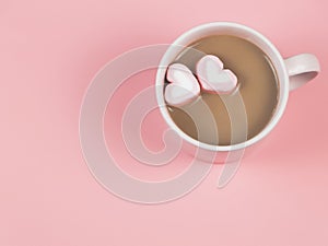 Hot chocolate with two heart shape marshmallows on pink background with copy space. Valentine`s day and beverage concept
