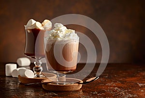 Hot chocolate with whipped cream in a glass mug on a old brown table