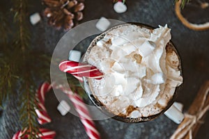 hot chocolate with whipped cream, marshmallows and red Lollipop on a black background, hot winter drink