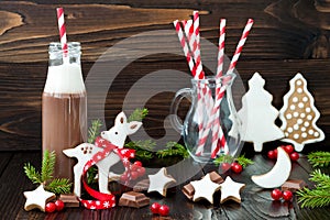 Hot chocolate with whipped cream in old-fashioned retro bottles with red striped straws. Christmas holiday drink and gingerbread