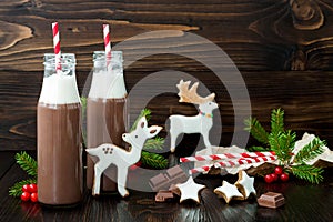 Hot chocolate with whipped cream in old-fashioned retro bottles with red striped straws. Christmas holiday drink and gingerbread