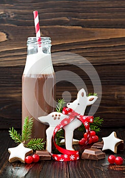 Hot chocolate with whipped cream in old-fashioned retro bottles with red striped straws. Christmas holiday drink and gingerbread b