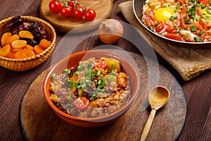 hot cholent sprinkled with green onions on a laid Shabbat table.