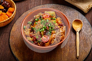 hot cholent sprinkled with green onions on a wooden stand with a spoon on a set Shabbat table.