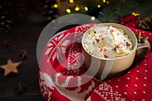 Hot christmas drink with cinnamon,cream,xmas lights and knitted pullover.