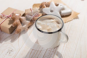 Hot Christmas drink with marshmallows in an iron mug and gingerbread cookies, on a white table. New Year, holiday background, copy