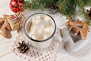 Hot Christmas drink with marshmallows in an iron mug and gingerbread cookies, on a white table. New Year, holiday background, copy