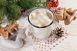 Hot Christmas drink with marshmallows in an iron mug and gingerbread cookies, on a white table. New Year, holiday background, copy