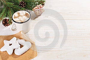 Hot Christmas drink with marshmallows in an iron mug and gingerbread cookies, on a white table. New Year, holiday background, copy