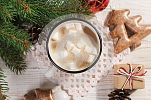 Hot Christmas drink with marshmallows in an iron mug and gingerbread cookies, on a white table. New Year, holiday background, copy