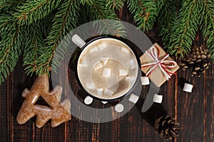 Hot Christmas drink with marshmallows in iron mug and gingerbread cookies, on a wooden table. New Year, holiday background,