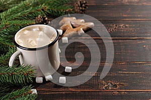Hot Christmas drink with marshmallows in iron mug and gingerbread cookies, on a wooden table. New Year, holiday background,