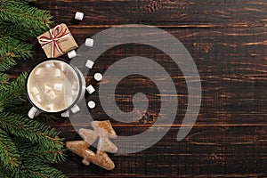 Hot Christmas drink with marshmallows in iron mug and gingerbread cookies, on a wooden table. New Year, holiday background,