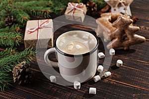 Hot Christmas drink with marshmallows in iron mug and gingerbread cookies, on a wooden table. New Year, holiday background,