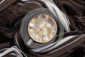 Hot Christmas drink with marshmallows in an iron mug, on a wooden table and a scarf. New Year, holiday background, greeting card