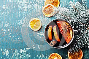 Hot christmas mulled wine or gluhwein with spices and orange slices on vintage teal table top view. Traditional drink on winter. photo