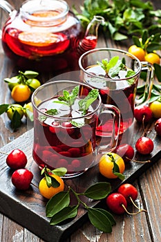 Hot citrus and berries tea, drink in glass cups and teapot with fresh mint leaves
