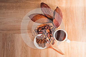 Hot cocoa cup with cocoa powder and cocoa beans on wooden background