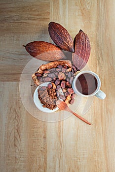 Hot cocoa cup with cocoa powder and cocoa beans on wooden background