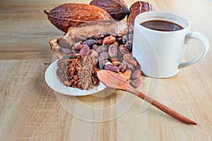 Hot cocoa cup with cocoa powder and cocoa beans on wooden background