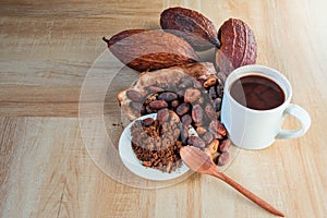 Hot cocoa cup with cocoa powder and cocoa beans on wooden background