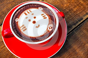 Hot cocoa and face cat milk foam in the red cup on wood background