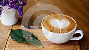 Hot coffee cappuccino latte art heart shape in ceramic cup on wood plate