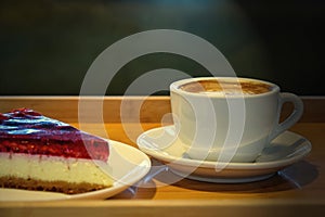 Hot coffee cappuccino latte with cheesecake on wooden background. Toned. Close-up