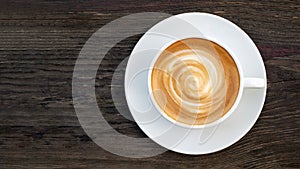 Hot coffee cappuccino latte spiral foam top view on dark wood background