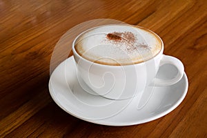 Hot coffee cappuccino latte in white ceramic cup on wooden table