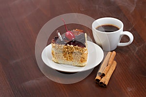 Hot coffee with cinnamon sticks and cake on a plate
