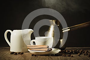 Hot coffee cup with cinnamon sticks with a creamer and old pot/hot coffee cup with cinnamon sticks with a creamer and old pot on a