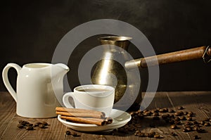 hot coffee cup with cinnamon sticks with a creamer and old pot/hot coffee cup with cinnamon sticks with a creamer and old pot on a