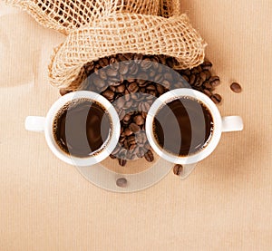 Hot coffee cup and coffee beans on brown background top view