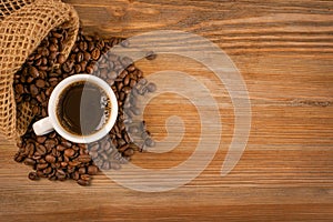 Hot coffee cup and coffee beans on brown background top view