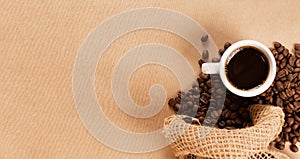 Hot coffee cup and coffee beans on brown background top view