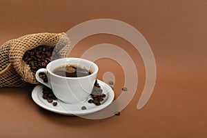 Hot coffee cup and coffee beans in burlap bag