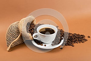 Hot coffee cup and coffee beans in burlap bag