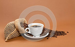 Hot coffee cup and coffee beans in burlap bag