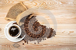 Hot coffee cup and coffee beans in burlap bag